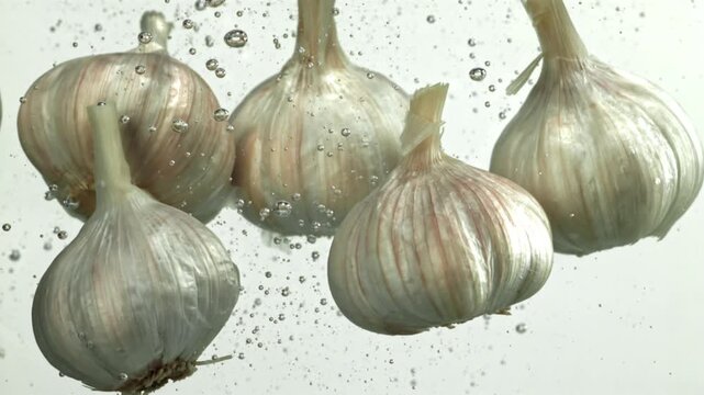 The heads of fresh garlic fall under the water. Filmed on a high-speed camera at 1000 fps. High quality FullHD footage