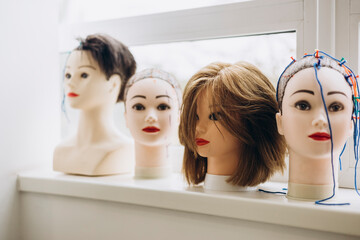 Multiple mannequin heads used for practicing haircuts and hairstyles.