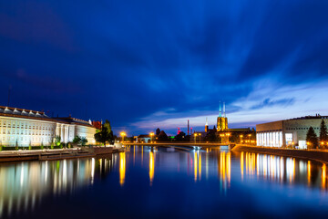 Wroclaw Skyline At Blue Hour With Cathedral Reflections On Odra River. Night Cityscape Lights And Travel Waterfront. Long Exposure Photography
