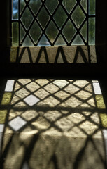 Diamond Leaded Glass Window Casting Patterned Sunlight Shadow on Stone Sill