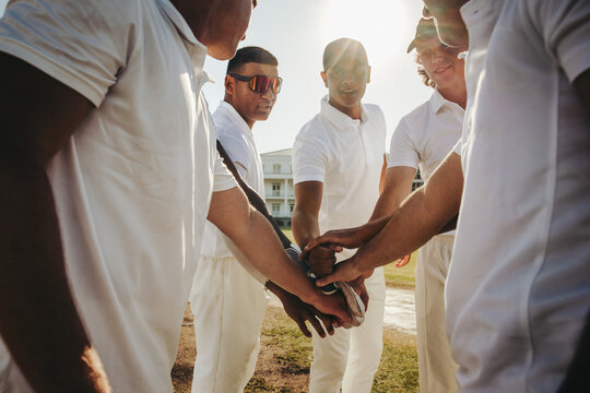 Cricket team huddle with united hands under sunny outdoor setting