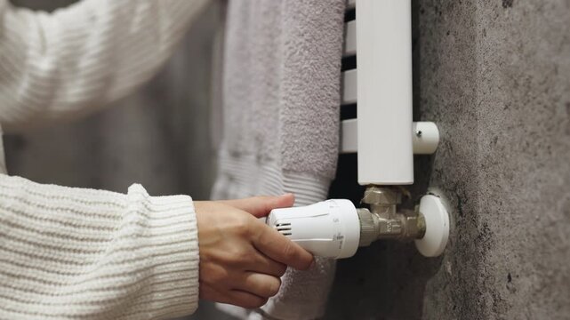 A hand adjusts a thermostat, highlighting temperature control and energy saving at home. Concept energy efficiency and comfortable living