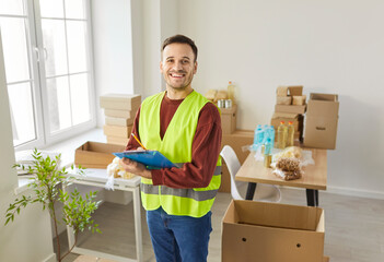 Happy male volunteer working in charitable food foundation, engaged in charitable work and donations, writing down notes in paperclip, distributing food in a warehouse. Humanitarian work concept