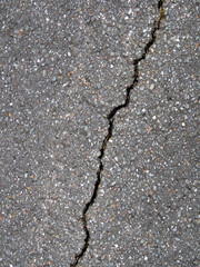 Nahaufnahme eines diagonalen Risses in schwarzem Asphalt