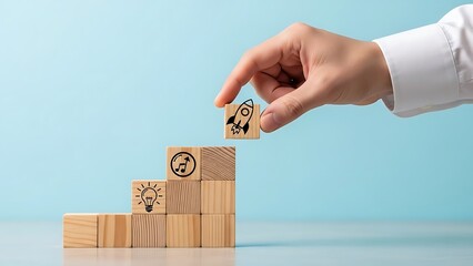 Hand placing rocket block on top of wooden block tower with idea and music note icons against blue