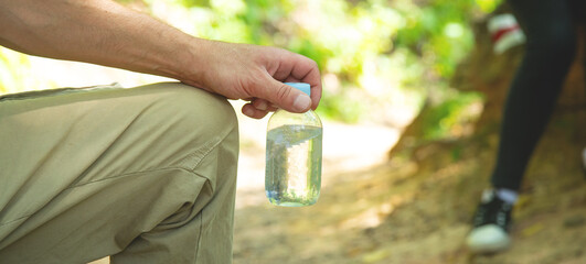 Human holding a bottle of clean water in nature.