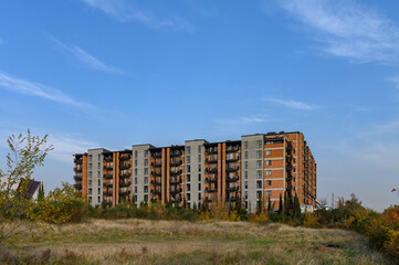 Fototapeta premium Modern Residential Complex, View from the Street or Courtyard. Building Surrounded by Urban Environment, Cars, Trees.