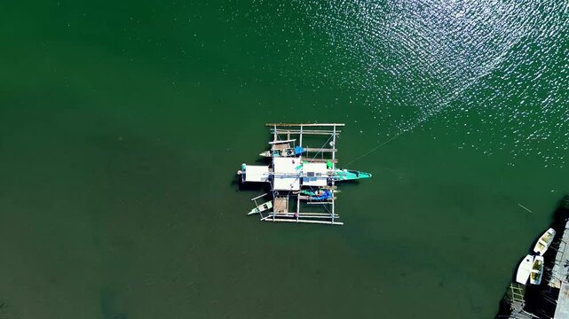 Look down drone shot from a traditional outrigger fishing boat slowly ascending to reveal the vast waters and bamboo harbor at Tambobo Bay. Siaton Negros Oriental, Philippines
