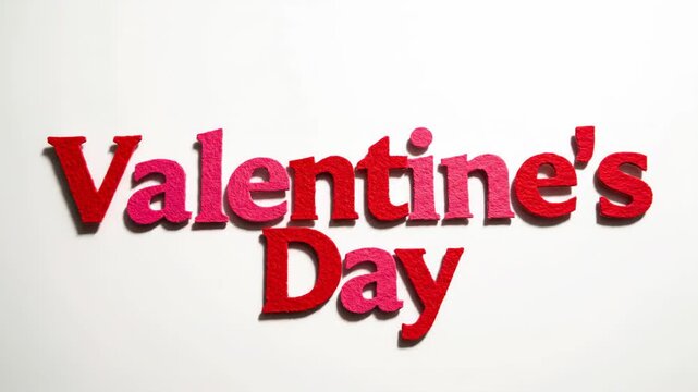 Valentine's Day text animation with red and pink felt letters. Stop motion footage of words assembling on a white background. Romantic holiday concept with copy space