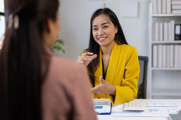 Obraz premium Businesswomen discussing projects together in the office, analyzing documents and charts.