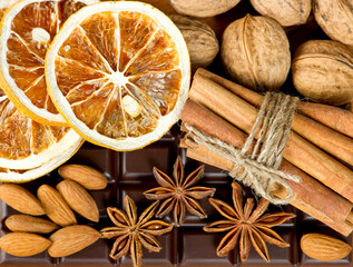 chocolate, cinnamon sticks, anise stars, nuts and sliced of dried orange. spices background. sweet food