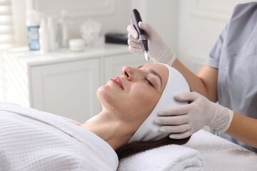 Woman undergoing microneedling procedure in beauty salon, closeup
