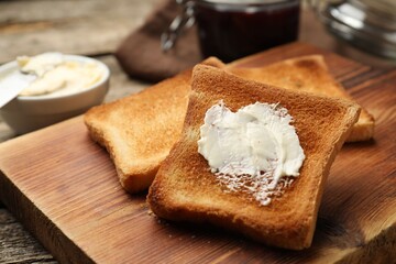 Slices of toasted bread with butter on wooden table, closeup