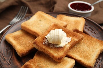 Slices of toasted bread, butter and jam on wooden table, closeup
