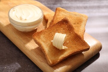 Fresh toasted bread slices with butter on grey table, closeup