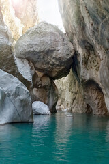 Massive boulder suspended between Goynuk canyon walls, Turkey. Stunning narrow gorge with hanging giant rock above turquoise waters.