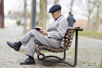 Elderly writer taking notes in notebook while sitting on park bench