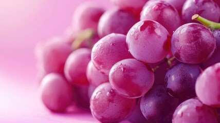 Juicy pink grapes resting on a simple pink surface showcasing their freshness and vibrant color during bright daylight