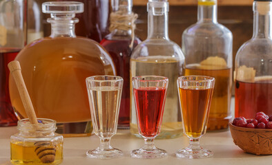 A set of homemade multicolored alcoholic tinctures and liqueurs in bottles and glasses. The bitters. Selective focus