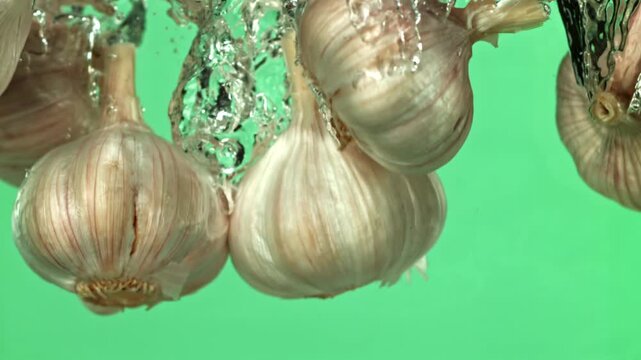 The heads of fresh garlic fall under the water. Filmed on a high-speed camera at 1000 fps. High quality FullHD footage