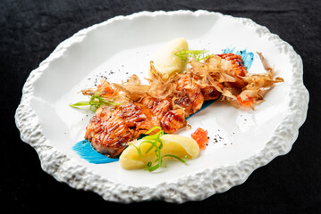 Gourmet pan-seared salmon with bonito flakes, creamy mashed potato puree, and red tobiko on a modern white plate, high angle view