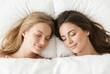 Young couple lying on bed in the morning, smiling woman resting her head on the pillow, dreaming of a relaxing, healthy life