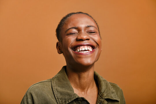 close up shot of Young black woman laughing with eyes closed in studio