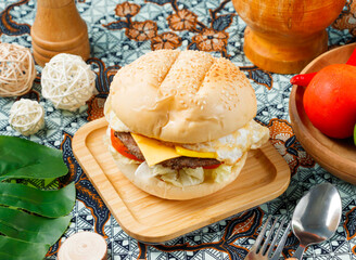 Mouthwatering burger topped with sunny-side egg and cheese on a wooden plate perfect for food bloggers and restaurant marketing promotion