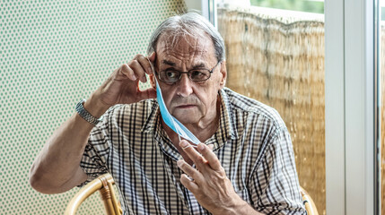 Senior man putting a protective mask on his face.
