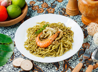 Succulent pesto seafood pasta featuring vibrant prawn and squid on traditional patterned linen