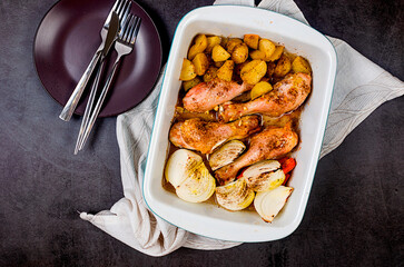 Roasted chicken legs and potatoes served in a baking dish