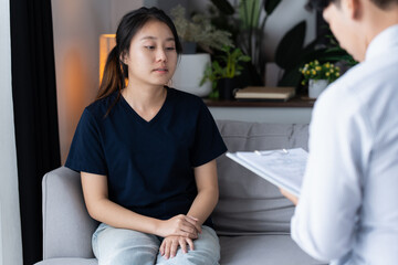 sad female sitting on sofa Patient discussing mental health issues with psychologist. depressed...