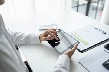 Business man holding digital tablet using Stock market application and reviews finances and manages budget with money cash