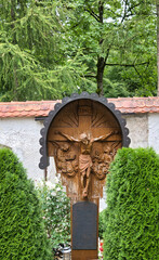 schönes reich verziertes Holzkreuz mit einem Dach auf einem Friedhof in Kaufbeuren © Blende8