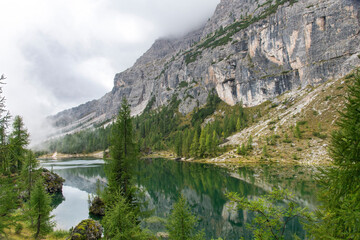 Fototapeta premium Reflections in tranquil water of Lake Federa alpine lake at foot of mountain Croda da Lago in Dolomite Alps or Pale Mountains named from carbonate rock dolomite near Cortina d'Ampezzo, Italy