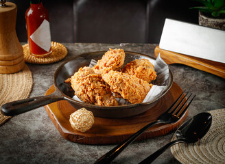 Delicious crispy fried chicken served in a rustic pan with hot sauce, perfect for restaurant menus and food blogs craving comfort food