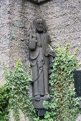 alte Jesusstatue mit Heiligenschein vor einer Wand auf  dem Katholischen Friedhof in Kempten Allgäu © Blende8