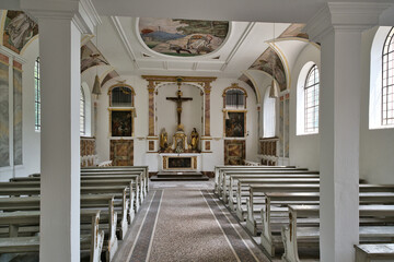 Innenansicht der Kapelle mit Bänken und dem weg zum Altar auf dem katholischen Friedhof in Kempten © Blende8
