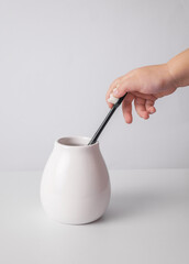Little child hand take toothbrush from a ceramic holder against a white background. Oral hygiene.