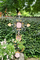 schön verziertes Eisenkreuz vor einer Wand aus Efeu auf dem Katholischen Friedhof in Kempten - Allgäu © Blende8