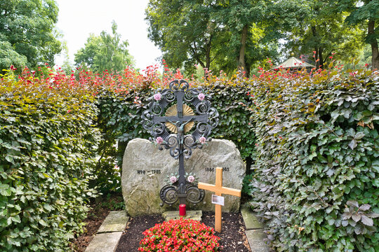 sch&ouml;nes Eisenkreuz ein schlichtes Holzkreuz und ein Stein umgeben von Hecken auf dem Katholischen Friedhof in Kempten - Allg&auml;u