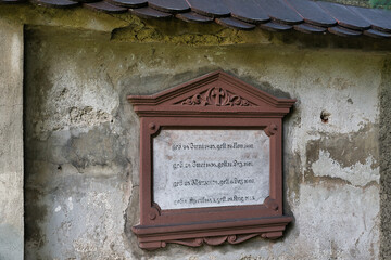 kleine Wandtafel anstelle eines Grabsteines an einer Mauer auf einem Waldfriedhof in Memmingen © Blende8