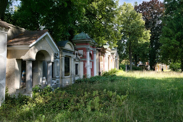 viele große Familiengräber an einer langen Mauer entlang schöne Begräbniskultur aus einem anderen Jahrhundert auf einem Waldfriedhof in Memmingen © Blende8