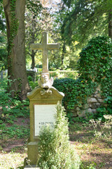 alter Grabstein mit einem Kreuz und einem Engelskopf auf dem Waldfriedhof in Memmingen © Blende8