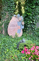 moderner roter Stein mit einer Blumenranke auf dem Waldfriedhof in Memmingen © Blende8