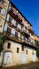 Charming Historic Building Facade in Montauban Architectural Style with Multiple Balconies and Shuttered Windows Under a Clear Blue Sky