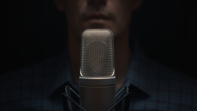 Close-up of a studio microphone. A man is in the background. Focus is on the microphone. Recording vocals, voiceover, or a podcast. Audio content creation techniques. - Powered by Adobe