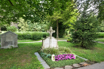 schöner sehr alter Grabstein mit vielen Blumen auf dem Waldfriedhof in Memmingen © Blende8