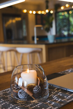 Bowl featuring burning pillar candle with seasonal accents sitting on kitchen island beside laptop