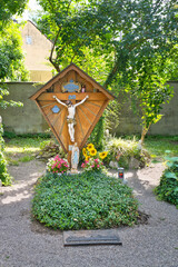 schönes Familiengrab mit einem Holzkreuz und der Jesusfigur und Sonnenblumen auf dem Waldfriedhof in Memmingen © Blende8
